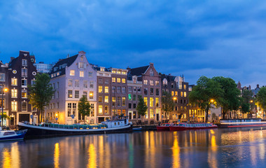 Fototapeta premium Night city view of Amsterdam canal, typical dutch houses and boats, Holland, Netherlands.