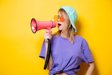 Young style girl in purple clothes with pink megaphone on yellow background. Symbolizes female...