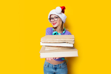 Young style girl in purple clothes and Christmas hat and books on yellow background.  Clothes in...