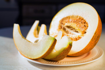 Half melon and melon slices on white plate close