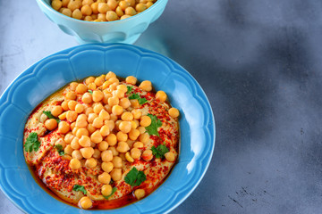 Chickpea hummus and tahini topped with olive oil, pepper, parsley, spices on a shabby modern table silver tray. Hummus Traditional Middle Eastern food commonly served in a pita.