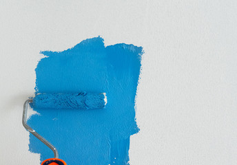 Someone painting white wall in blue color