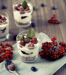 Healthy breakfast - yogurt with fresh berries and muesli served in glass jar, on wooden background