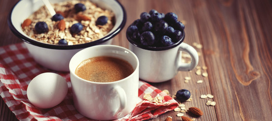 A healthy breakfast is a great start to a new day. Oatmeal porridge, coffee, berries and nuts on a wooden table.