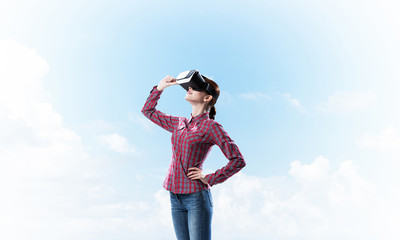 Girl in checked shirt wearing VR glasses experiencing another re
