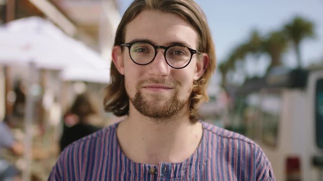 portrait of attractive geeky man smiling confident on beachfront