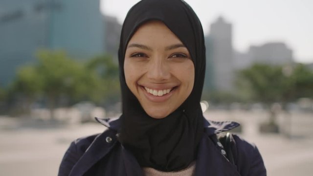 close up portrait of young happy muslim business woman wearing hajib headscarf laughing cheerful in city