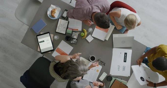 diverse business people graphic designers working startup company project brainstorming ideas using logo designs in office boardroom meeting top view