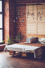 Simple bedroom with double bed, red brick wall and big window