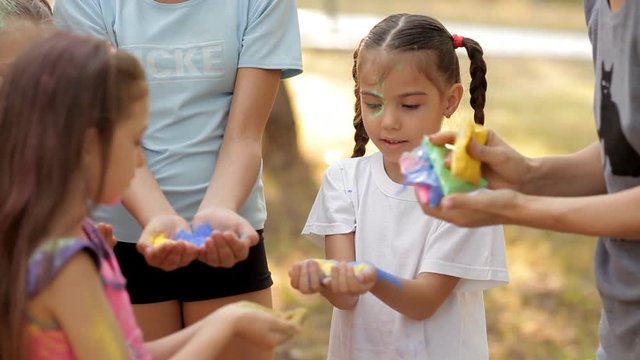 On a sunny summer day, children spend time on the lawn, children are given a colorful sand for the game. Fun.Leto. Festival of Spring