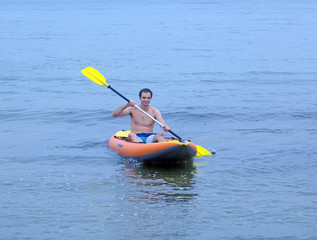 young man in sea is smiling while sailing a kayak