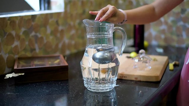 A metal strainer put down into a glass jug full of water.