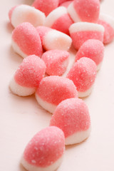 Pink jellies or marshmallows with sugar on table