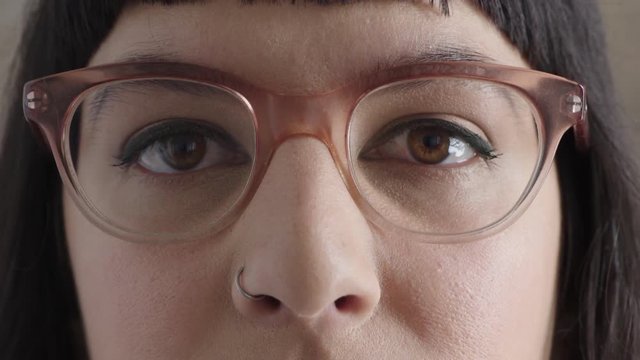 close up portrait of young hipster woman eyes looking serious at camera wearing stylish glasses vision eyesight