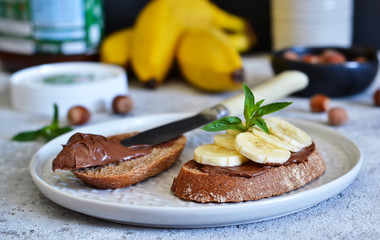 Grilled toast with chocolate paste and banana for breakfast on a concrete background.