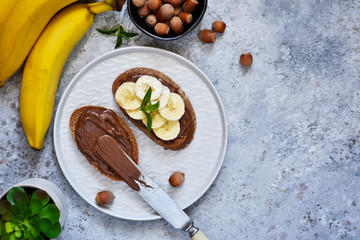 Grilled toast with chocolate paste and banana for breakfast on a concrete background.