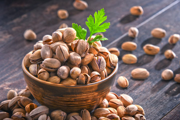 Composition with bowl of pistachio on wooden table. Delicacies