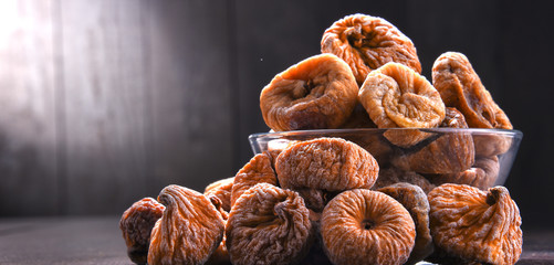 Composition with bowl of dried figs on wooden table