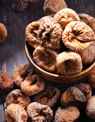 Composition with bowl of dried figs on wooden table