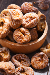 Composition with bowl of dried figs on wooden table