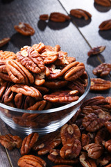 Bowl with pecan nuts on wooden table.
