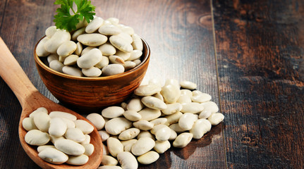 Composition with bowl of white beans on wooden table