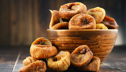 Composition with bowl of dried figs on wooden table