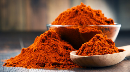 Composition with bowl of chili powder on wooden table