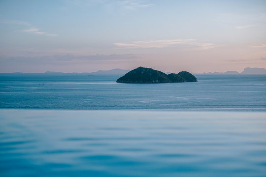 Scenic view of sunset from Infinity Pool overlooking calm sea water with fishing boats around the mini island.