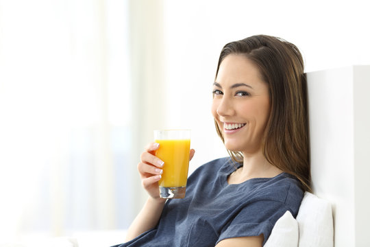 Woman looking at camera holding orange juice