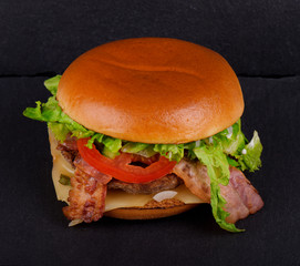 Fresh tasty burger, on black stone background.