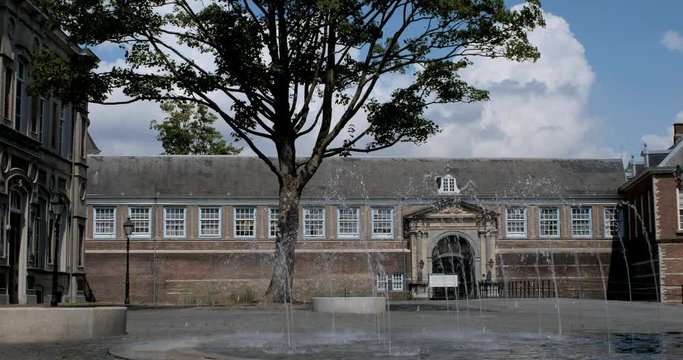 Breda Castle with fountain on a windy day. The castle dates back to the 14th century and houses the Royal Military Academy since 1826. Breda, Netherlands, July 2018.