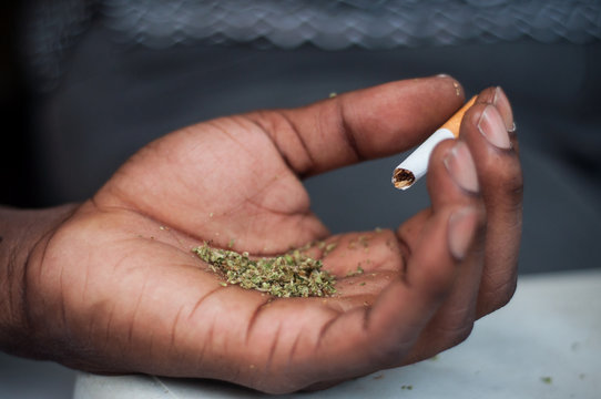 closeup of african man rolling a joint of cannabis in outdoor