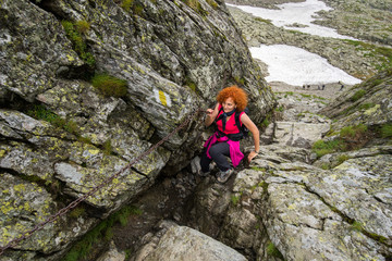 Naklejka na ściany i meble Woman hiking into rocky mountains