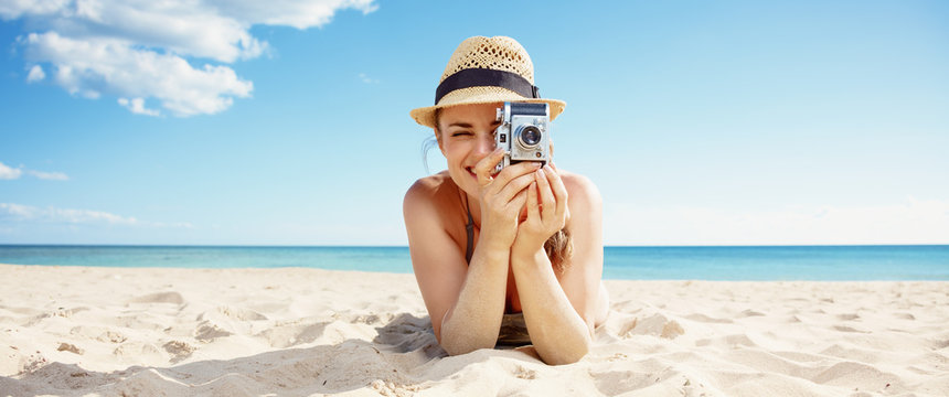 happy woman taking photo with retro photo camera on seacoast