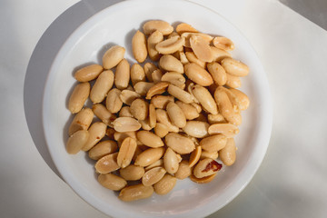 Tasty peeled peanuts on a white plate