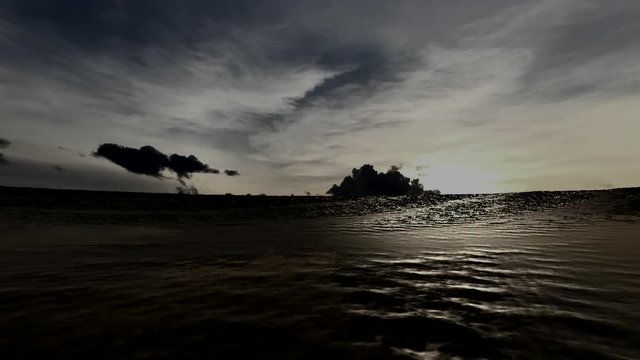 Animated video shows a sunset over a tropical island and sunlight glistening off the surface of the ocean surface at dusk.
