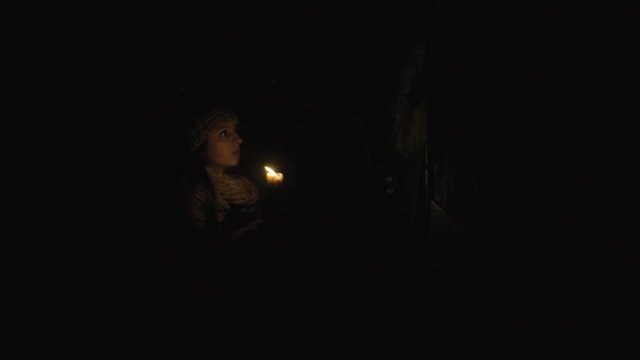 horror - girl with a candle in a dark basement