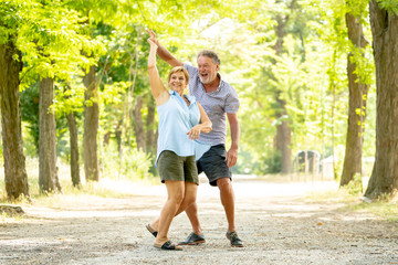 Happy smiling senior couple in love, dancing and having fun in the park. Being together, in love, retirement happy life concept.