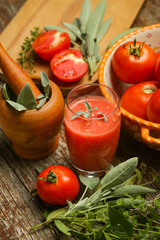 Glass of fresh tomato juice with herbs on the wooden table. Healthy organic nutrition concept.

