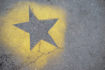 the yellow star is painted on gray asphalt