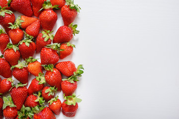 strawberry fruits on the left side on wooden background with copy space. View from above.