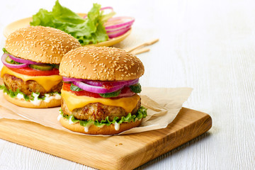 Two burgers on cutting board