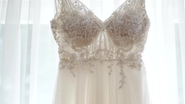 Beautiful White Brides Dress Hanging On The Window In Bride's Room