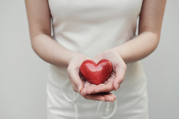 Young woman holding red heart, health insurance, donation concept