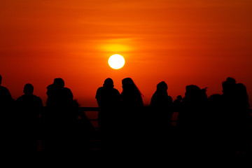 Fototapeta na wymiar Silhouettes of people at sunset in front of the Pacific Ocean in the neighborhood of Miraflores (Lima, Peru)