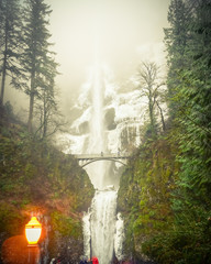 Fototapeta premium Vintage tone crowded of visitor at the main lookout of the base of Multnomah Falls in winter time. A waterfall on the Oregon side of the Columbia River Gorge, along the Historic Columbia River Highway