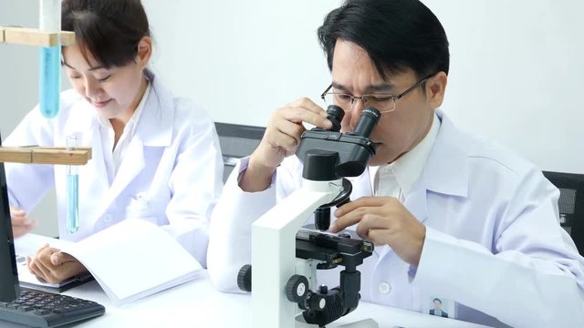 Asian Scientist use microscope for work at laboratory. People with medical, science, doctor, healthcare concept. 4K Resolution.