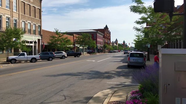 A woman crosses a street in small town in Ohio as seen from the main street