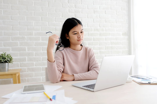  Young asian woman working with laptop computer at home office with happy emotion, working from home, small business, office casual lifestyle concept